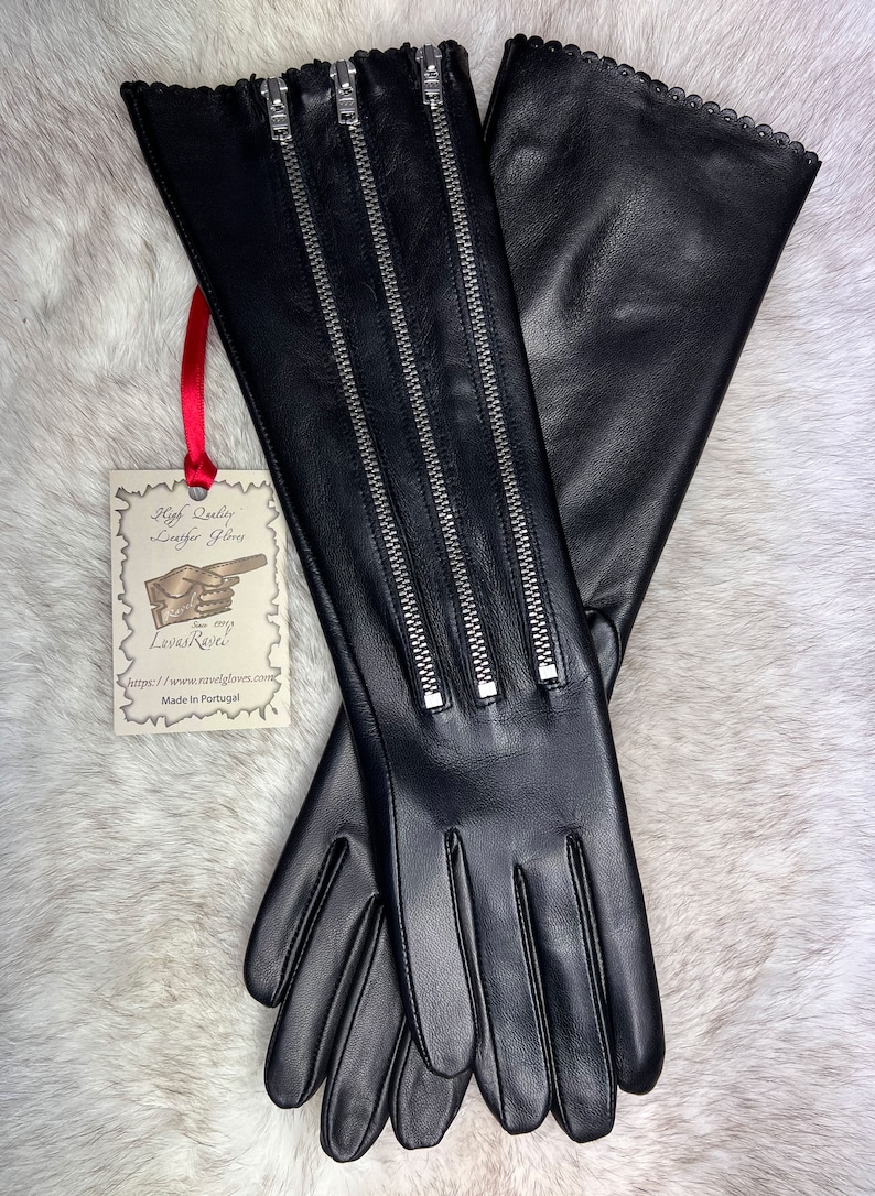 May include: Black leather gloves with three zippers on the back of the hand. The gloves have a scalloped edge and are made in Portugal.