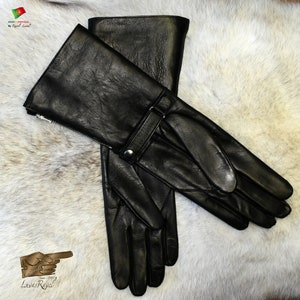 May include: A pair of black leather gloves with a long cuff and a strap with a buckle. The gloves have a zipper on the cuff and are made in Portugal.