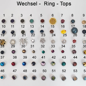 Op de afbeelding: Een verzameling van 54 decoratieve ringtoppen in diverse kleuren en ontwerpen, waaronder edelstenen, parels en metallic afwerkingen. De toppen zijn gerangschikt in rijen en kolommen op een witte ondergrond.