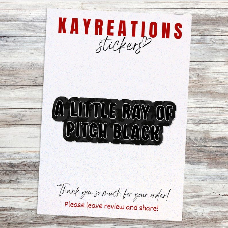 May include: A sticker featuring the phrase "A LITTLE RAY OF PITCH BLACK" in a black and white design. The sticker is on a white background with the words "KAYREATIONS stickers" in red. Below the sticker is the text "Thank you so much for your order! Please leave review and share!"