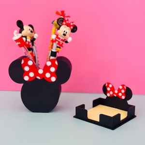 Puede incluir: Juego de organizadores de escritorio negros con tem&aacute;tica de Minnie Mouse. Incluye un portal&aacute;pices con forma de cabeza de Minnie con un lazo de lunares rojos y blancos, y un portanotas. Bol&iacute;grafos con figuras de Minnie Mouse est&aacute;n en el portal&aacute;pices.