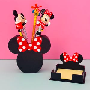 Puede incluir: Juego de organizador de escritorio negro con tem&aacute;tica de Minnie Mouse. El juego incluye un portal&aacute;pices con la silueta de Minnie y un lazo rojo con lunares blancos, y un portabloques de notas. El portal&aacute;pices contiene bol&iacute;grafos con adornos de personajes de dibujos animados.