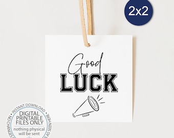 May include: A white printable tag with black text that reads "Good Luck" with a black and white megaphone graphic. The tag is 2 inches by 2 inches.