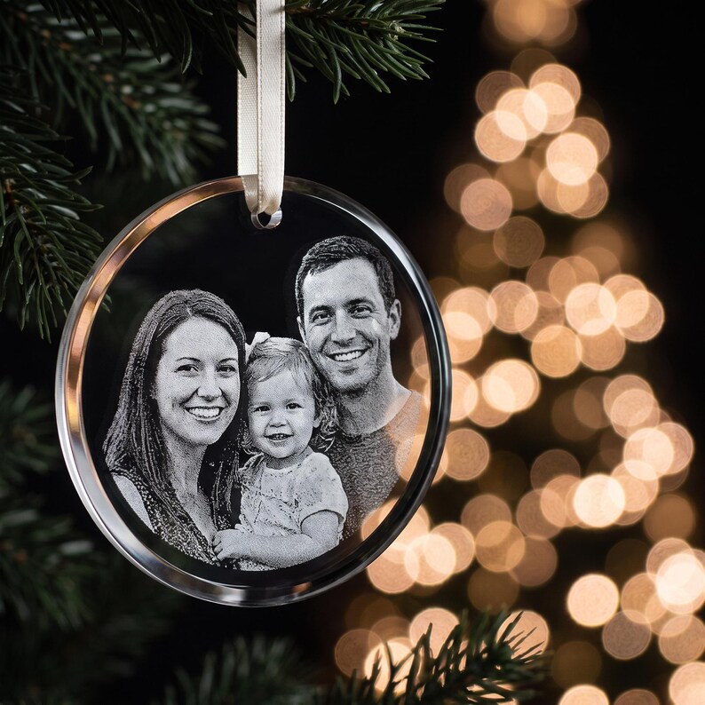 Circle photo crystal ornament hanging on a Christmas tree, engraved with a family portrait.