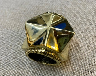 May include: A gold-colored, star-shaped ring with a textured edge. The ring is made of metal and has a hollow center.