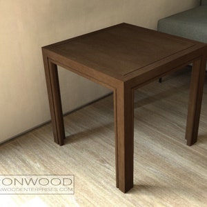May include: A dark brown wooden end table with a square top and four legs. The table has a simple design and is made of solid wood.