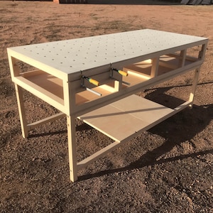 May include: A light wood workbench with a pegboard top and a lower shelf. The workbench is rectangular in shape and is supported by four legs.
