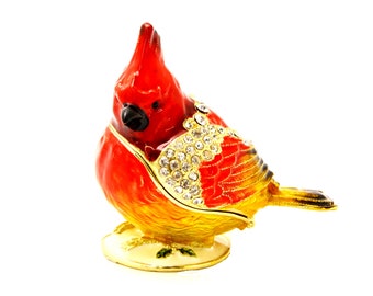 May include: A red cardinal bird figurine with gold accents and rhinestones. The figurine is a trinket box with a hinged lid.