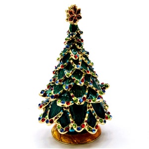 Könnte beinhalten: Eine grüne Weihnachtsbaum-Schmuckschatulle mit goldener Basis und einem Stern oben. Der Baum ist mit bunten Strasssteinen verziert.