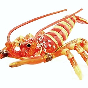 May include: A red and yellow lobster figurine with a jeweled design. The lobster is made of metal and has a shiny finish.