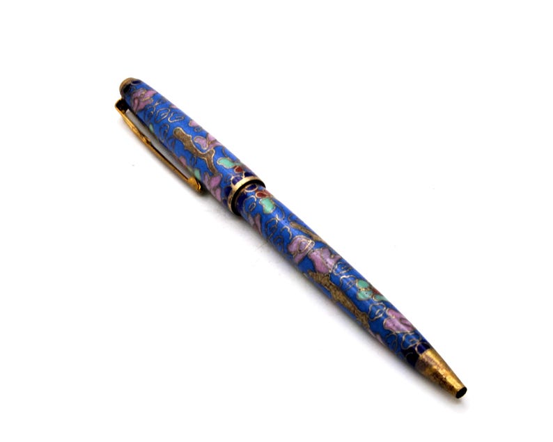 Puede incluir: Un bol&iacute;grafo azul con un dise&ntilde;o floral en rosa, verde y dorado. El bol&iacute;grafo tiene un clip y detalles dorados. Es un instrumento de escritura.