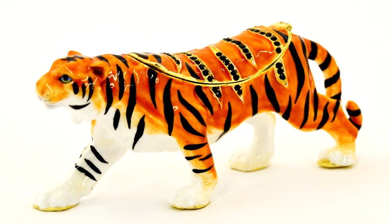 May include: A detailed orange and black tiger figurine with gold accents. The figurine is made of ceramic and has a jeweled lid. It is a decorative trinket box.