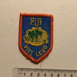 May include: Embroidered patch with a blue shield shape, orange border, and text. The patch features the text "EUi" at the top and "VITL LEVO" at the bottom. A central design depicts green trees and a landscape.