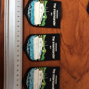 May include: Three black and green patches with the text "ARAHURA The Interislander N.Z." and a white ship illustration.