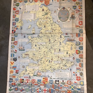 以下が含まれることがあります： イギリスとウェールズのヴィンテージマップで、カラフルな紋章がマップを囲んでいます。マップは紙に印刷されており、黄ばんだ外観をしています。マップには、イギリスとウェールズ全土の都市や町の名前が記載されています。