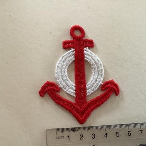 Könnte beinhalten: Rote und weiße gestickte Anker mit einem weißen Kreis in der Mitte. Der Anker ist etwa 5 cm hoch.