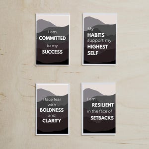 May include: Four rectangular cards with motivational quotes. Each card features a mountain landscape design in shades of gray and white. The quotes include "I am committed to my success," "My habits support my highest self," "I face fear with boldness and clarity," and "I am resilient in the face of setbacks."