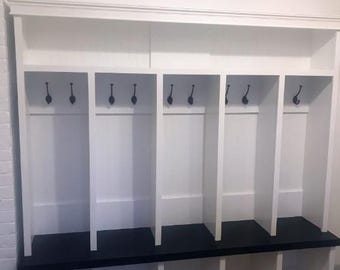 May include: A white wooden storage unit with six cubbies and six coat hooks. The unit has a black base and a shelf above the cubbies. The top of the unit has a decorative moulding. The letters "FDG" are in the top left corner.