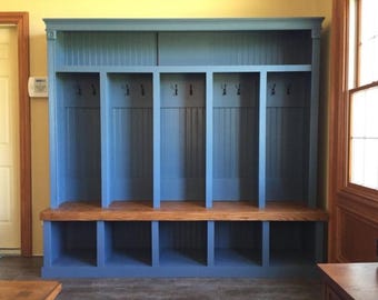 May include: A blue wooden entryway storage unit with multiple compartments. It features hooks for hanging items, a bench, and cubby storage below. The unit is painted blue with a natural wood bench top.