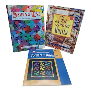Op de afbeelding: Drie quiltboeken worden getoond. De covers tonen kleurrijke quiltpatronen en titels als "Sewing on the Line", "Fat Quarter Quilts" en "Borders & Bindings". De boeken zijn voor liefhebbers van quilten.