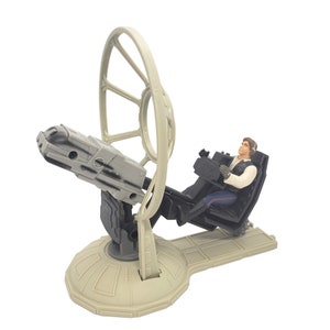 Pode incluir: Um conjunto de brinquedos de plástico bege com uma torre giratória com um blaster cinza e uma figura de Han Solo no assento do piloto.