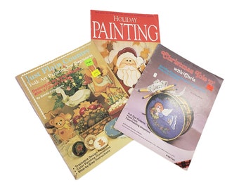 May include: Three craft books with colourful covers featuring holiday-themed painting projects. The titles are "Just Plain Country", "Holiday Painting", and "Christmas Tole 'w' with Chris".
