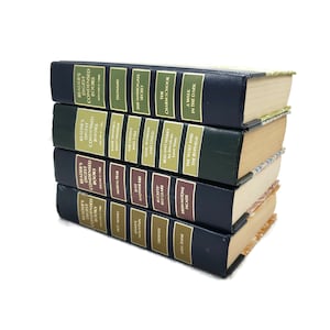 Op de afbeelding: Een stapel van zes blauwe en groene hardcover boeken met gouden letters. De boeken zijn allemaal Reader's Digest Condensed Books. De titels van de boeken zijn: "Tsunami!", "Het geheim van Harrogate", "The Charm School", "Een wandeling in het donker", "De wolf en de buffel" en "Brownstone Facade".