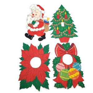 May include: Set of four vintage Christmas paper cutouts. The set includes a Santa Claus, a Christmas tree, a poinsettia, and a wreath with a red bow and ornaments.