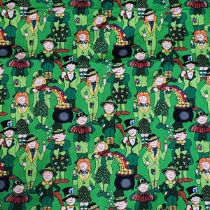 Op de afbeelding: Groene stof met een herhaald patroon van cartoon leprechauns. De leprechauns dragen groene pakken, hoeden en vlinderdassen, sommigen houden klavers vast of spelen accordeon. Een regenboog leidt naar een pot met goud in het ontwerp.