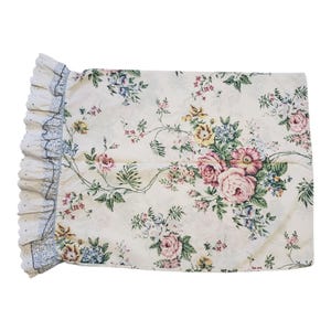 May include: A white pillowcase with a floral pattern featuring pink, yellow, and blue flowers. The pillowcase has a white lace trim with a blue border.
