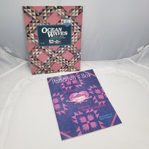 Puede incluir: Dos libros de patrones de acolchado. El primer libro se titula "Ocean Waves" y presenta un patr&oacute;n de acolchado rosa y marr&oacute;n. El segundo libro se titula "Pandora's Box" y presenta un patr&oacute;n de acolchado azul y rosa.