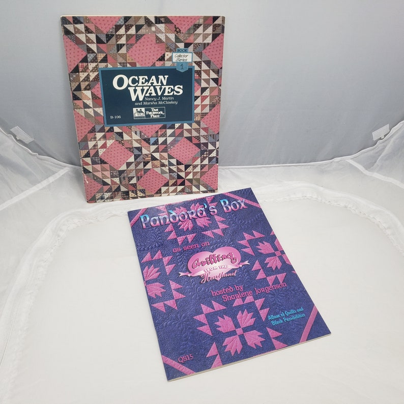 Puede incluir: Dos libros de patrones de acolchado. El primer libro se titula "Ocean Waves" y presenta un patr&oacute;n de acolchado rosa y marr&oacute;n. El segundo libro se titula "Pandora's Box" y presenta un patr&oacute;n de acolchado azul y rosa.