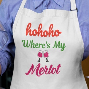 May include: White apron with the text "hohoho Where's My Merlot" embroidered in red, green, and pink. Two wine glasses are embroidered in red and white.