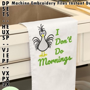 Puede incluir: Toalla de cocina blanca con un diseño de gallina de dibujos animados y el texto verde "I Don't Do Mornings". La toalla está doblada sobre una encimera blanca, con un fregadero y utensilios de madera en el fondo.