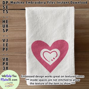 May include: A white towel with a pink heart design. The heart has a smaller heart inside of it. The text "Embossed design works great on textured items *** inside spaces are not stitched to allow the texture of the item to show ***" is printed below the heart.