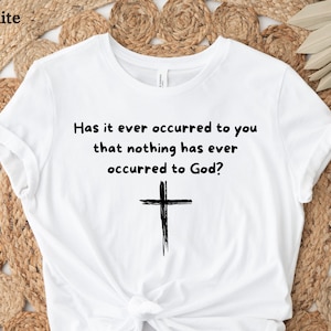 May include: White t-shirt with a black cross and the text "Has it ever occurred to you that nothing has ever occurred to God?"