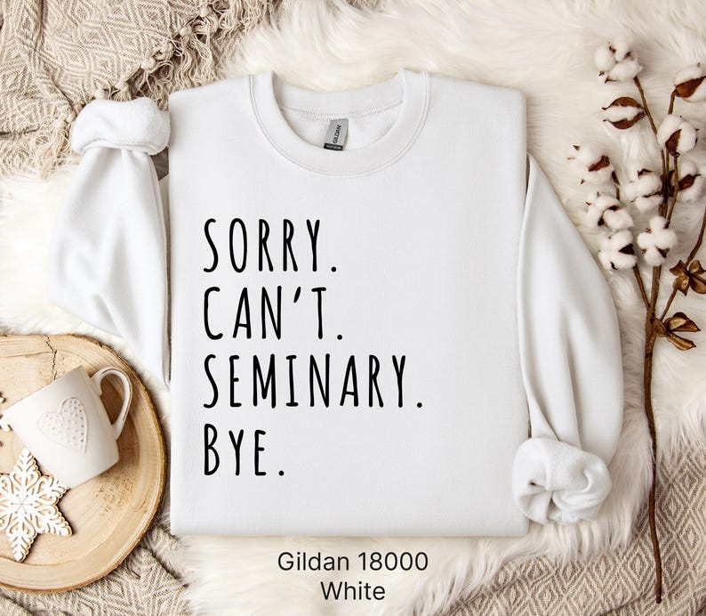 Op de afbeelding: Wit sweatshirt met de tekst "Sorry. Can't. Seminary. Bye." gedrukt op de voorkant. Het sweatshirt is gemaakt door Gildan en is maat 18000.