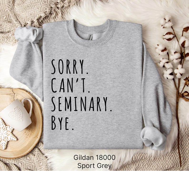 Op de afbeelding: Grijs sweatshirt met de tekst "SORRY. CAN'T. SEMINARY. BYE." gedrukt op de voorkant. Gildan 18000 Sport Grey.