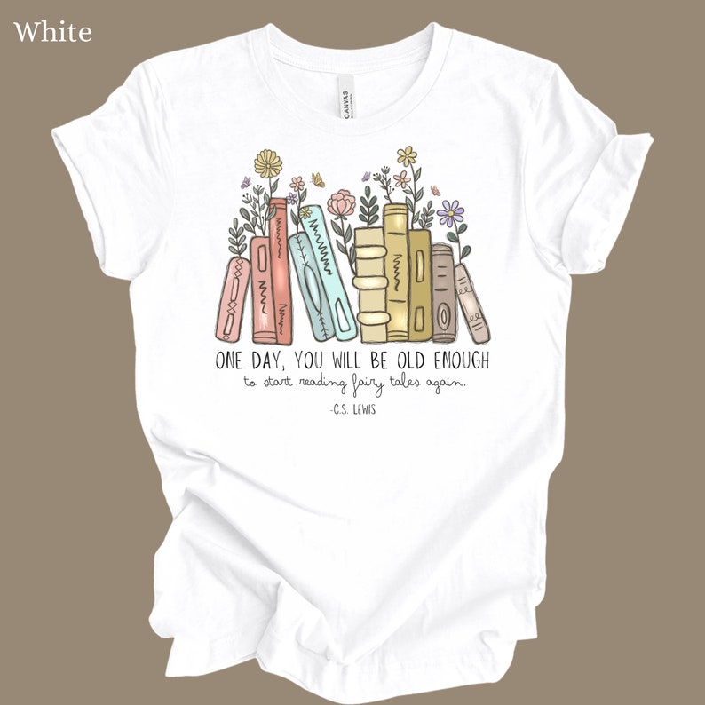 May include: White t-shirt with a graphic of a stack of books with flowers and the quote "ONE DAY, YOU WILL BE OLD ENOUGH to start reading fairy tales again - C.S. LEWIS"