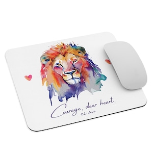 May include: A white mouse pad with a watercolor painting of a lion's head in shades of orange, red, yellow, blue, and purple. The lion's eyes are closed and the quote "Courage, dear heart. - C.S. Lewis" is written in purple below the lion.
