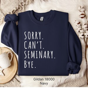 Op de afbeelding: Donkerblauwe sweatshirt met de tekst "SORRY. CAN'T. SEMINARY. BYE." in wit.