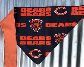 May include: A black and orange dog bandana with the words "Bears" and a bear logo repeated throughout. The bandana has a solid orange border.