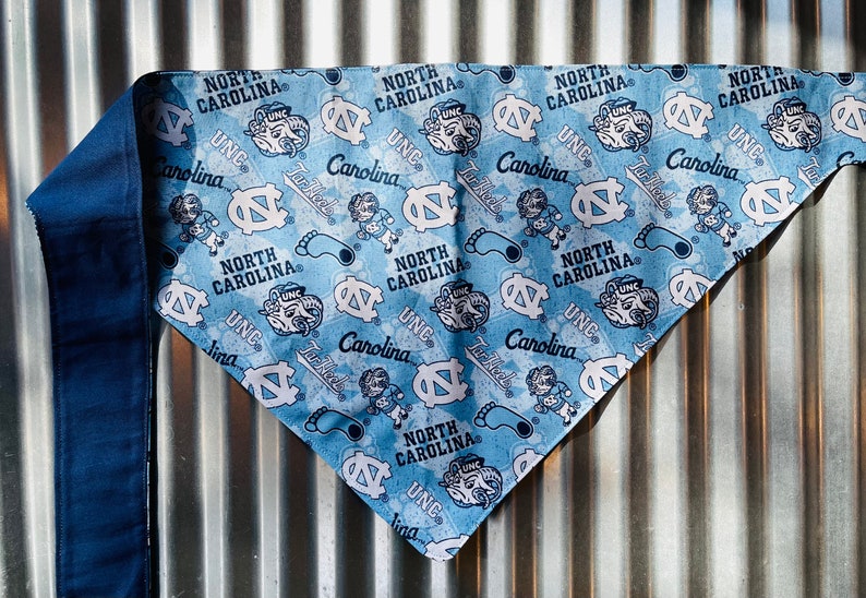 May include: A blue and white bandana with a repeated pattern of the North Carolina Tar Heels logo and the words "North Carolina" and "UNC".