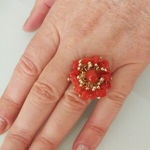 May include: A gold ring with a large red coral flower design. The coral is arranged in a cluster of small, round pieces.