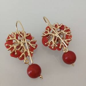 May include: A pair of gold earrings with red coral branches and red coral beads hanging from the bottom.
