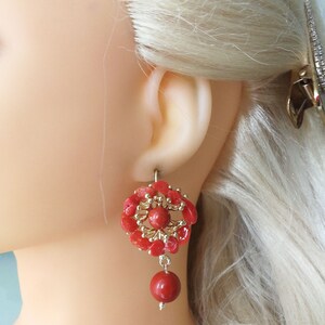 May include: Coral earrings with a gold-toned flower design and a single coral bead dangling from the bottom.