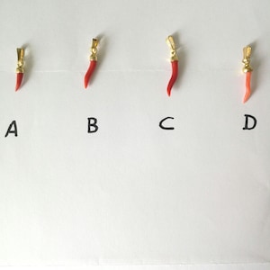 Peut inclure: Quatre breloques en forme de corne en corail rouge et or, étiquetées A, B, C et D.