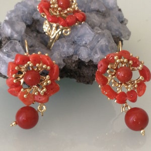 May include: A set of coral jewelry featuring a ring and earrings. The ring and earrings are made of gold and have a floral design with red coral stones.
