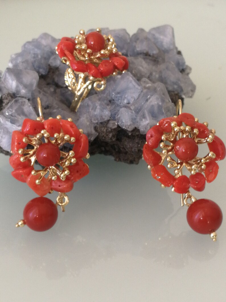 May include: A set of coral jewelry featuring a ring and earrings. The ring and earrings are made of gold and have a floral design with red coral stones.