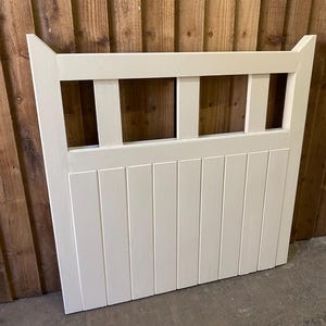 May include: White wooden gate with a slatted design and a decorative top. The gate has four rectangular openings in the top section.